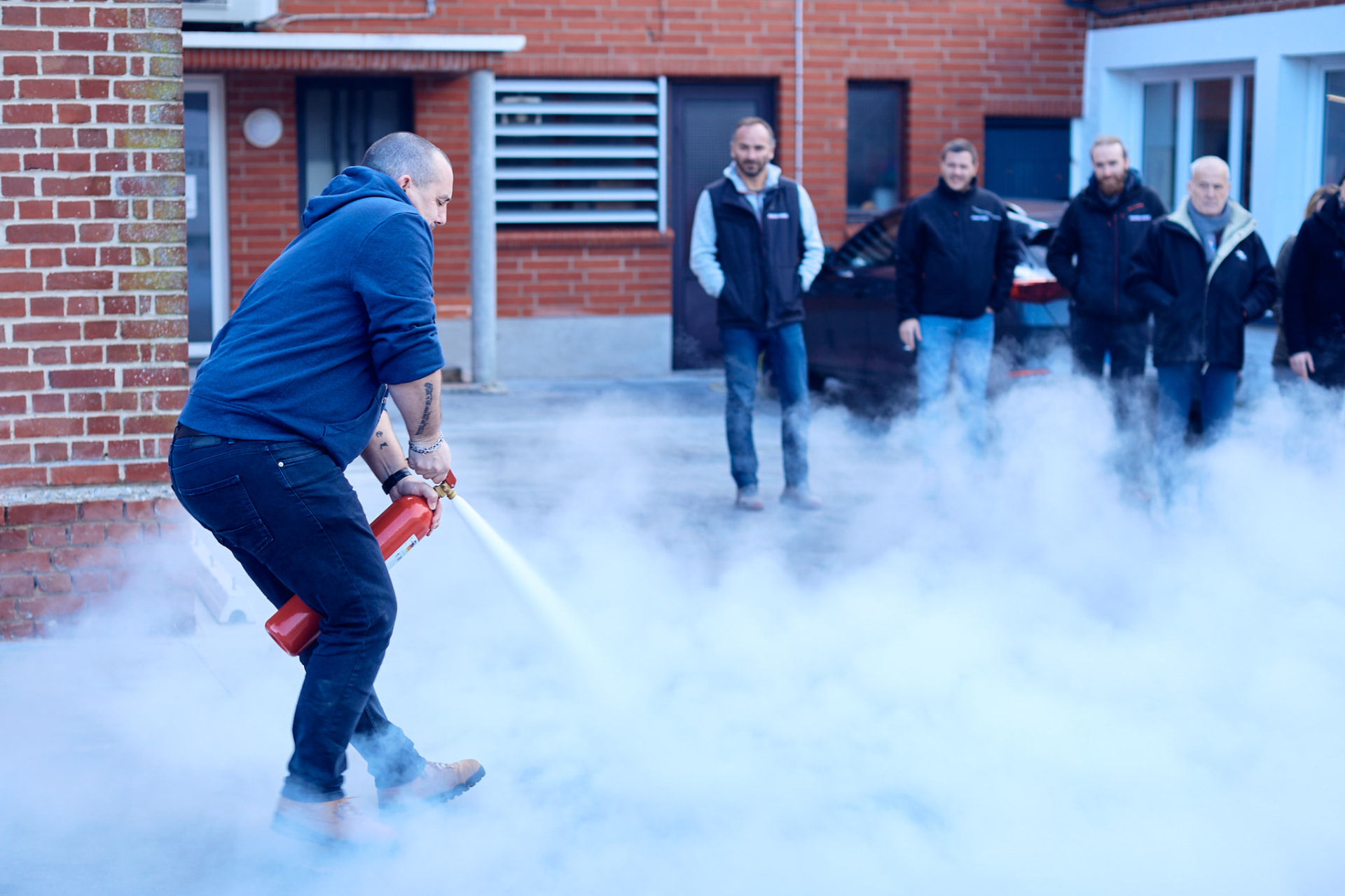 Exercice d'évacuation incendie en extérieur, groupe observant une extinction de feu